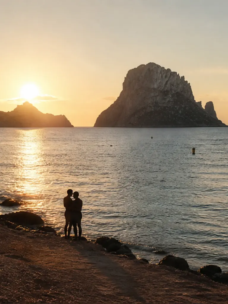 Es Vedrà rock seen from quiet Cala d’Hort at soft sunset, calm Mediterranean proposal atmosphere