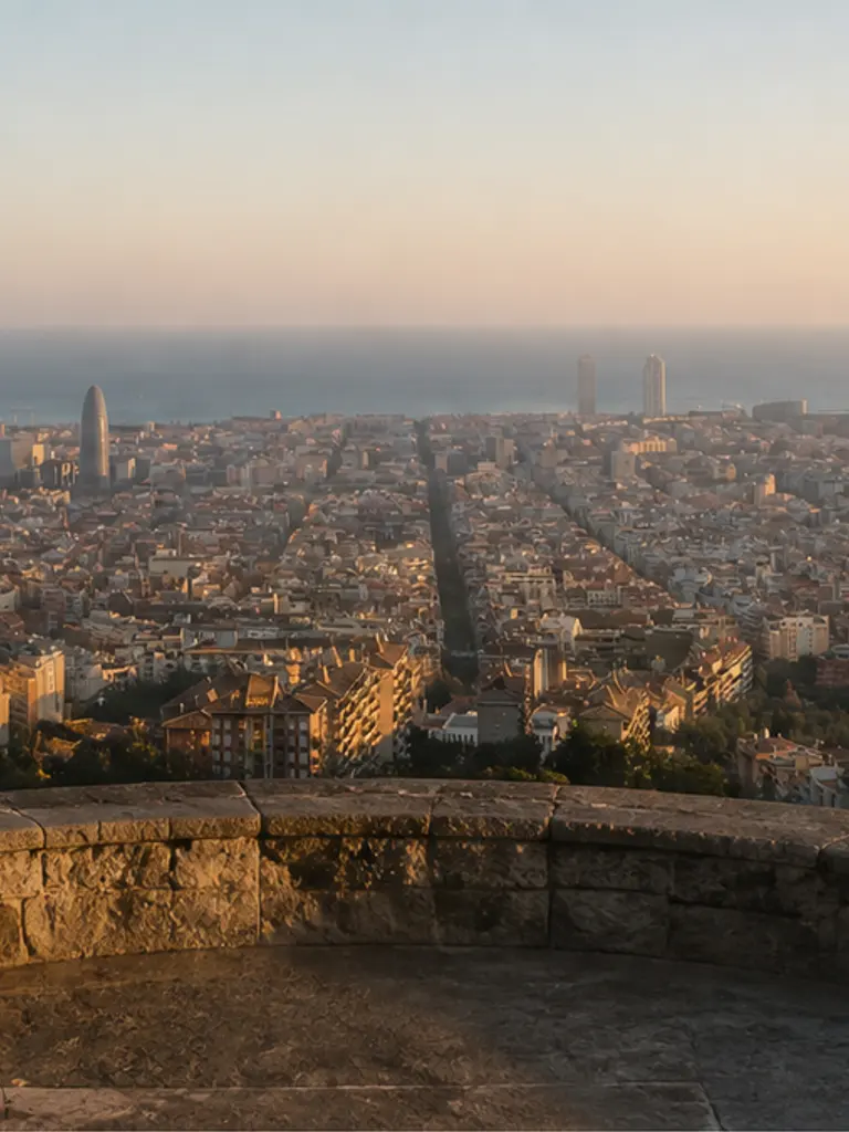 Barcelona city panorama from Turó de la Rovira at soft golden hour, empty quiet-luxury proposal viewpoint