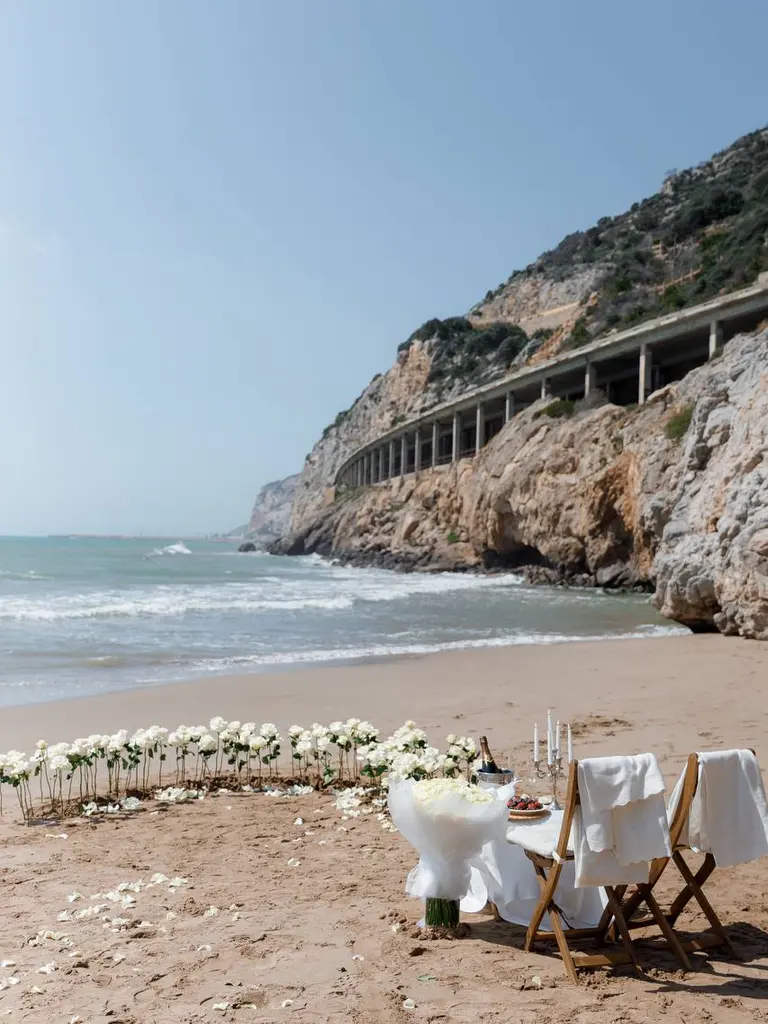 Ginesta beach marriage proposal setup with white roses and cliffs 1